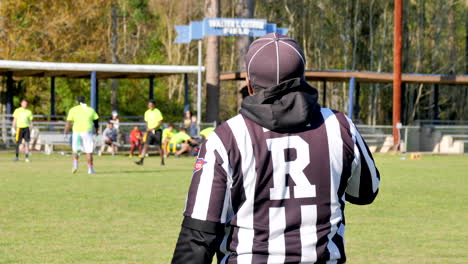 Referee-Making-a-Call-while-Young-Adults-Play-Flag-Football-on-a-Green-Field-on-a-Sunny-Day-in-the-City