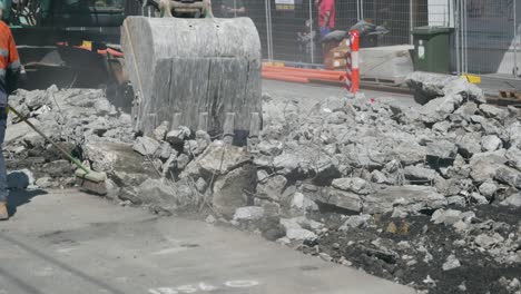 Workman-sweeping-as-digger-breaks-road-concrete-to-replace-tram-lines
