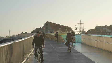 Los-Ciclistas-Pasan-En-Bicicleta-Por-Un-Puente-En-Copenhague,-Dinamarca,-Durante-Una-Hermosa-Tarde.