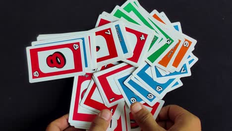 Männliche-Hände-Legen-Bunte-Uno-Spielkarten-Auf-Einem-Schwarzen-Tisch-Aus