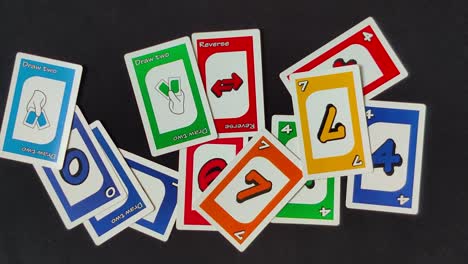 Overlay-panning-shot-of-several-Uno-cards-scaterred-on-a-black-table