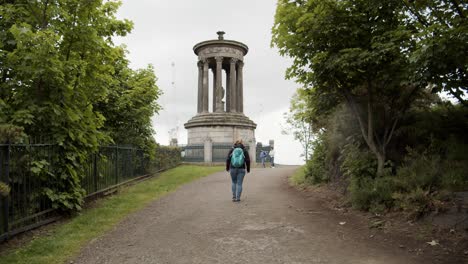 A-girl-with-red-hair-walks-towards-a-pillar-in-Edinburgh
