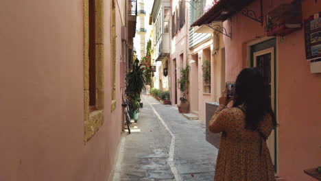 Chica-De-Pelo-Negro-Haciendo-Una-Foto-De-Una-Torre-En-Una-Calle-Acogedora-En-Creta,-Grecia