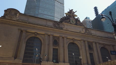 New-York's-Grand-Central-station-filmed-from-outside-on-the-pavement-with-people-passing-by,-tilting-upwards-towards-the-clockwork