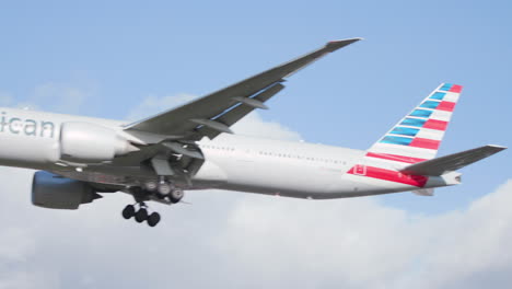 American-Airlines-plane-comes-in-to-land-at-London-Heathrow-Airport-on-a-sunny-day,-some-clouds