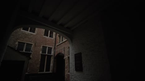 Moving-Forward-Through-Dark-Archway-into-Eerie-Courtyard,-Old-Building