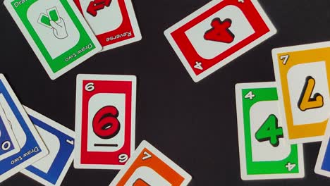 Overlay-Schwenkaufnahme-Mehrerer-Uno-Karten,-Die-Auf-Einem-Schwarzen-Tisch-Verstreut-Sind