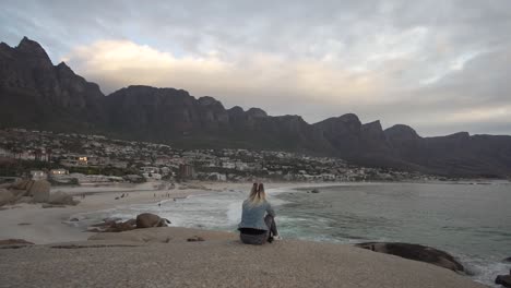 Frau-Blickt-In-Zeitlupe-Auf-Die-Küste-Von-Kapstadt-Mit-Dem-Tafelberg-Im-Hintergrund-Bei-Sonnenuntergang