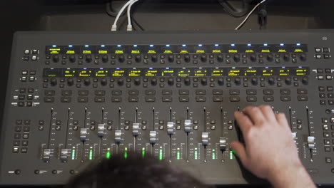 An-audio-engineer-operating-on-an-audio-mixer-filmed-from-above