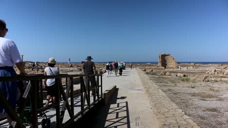 Gruppe-Von-Touristen,-Die-Im-Archäologischen-Park-Von-Paphos-Zwischen-Ruinen-In-Richtung-Küste-Gehen