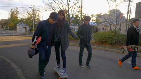 Cooler-Junger-Mann,-Der-Eine-Süße-Japanerin-Auf-Einem-Skateboard-Antreibt