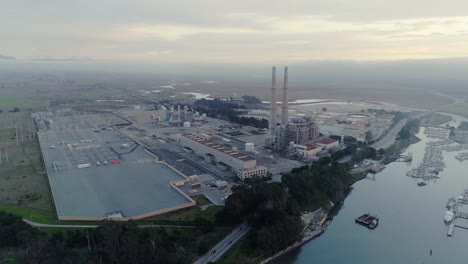 Aerial-Distant-Orbit-Shot-of-Power-Plant-and-Distant-Smog-at-Dusk