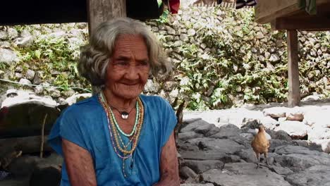 Eine-Einheimische-Alte-Philippinische-Frau-Aus-Ifugao-Bataad-Unterhält-Sich-Im-Sommer-Mit-Jemandem,-Der-Unter-Einer-Grashütte-Sitzt