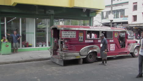 Jeepney-Icónico-Rojo-Que-Sale-Con-Pasajeros-En-La-Ciudad-De-Olongapo,-Zambales,-Filipinas