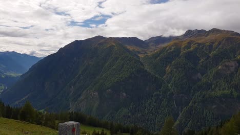 Conduciendo-Por-La-Carretera-Alpina-Grossglockner-En-Austria-Y-Pasando-Un-Coche-Blanco-Parado-Frente-A-Unas-Hermosas-Montañas