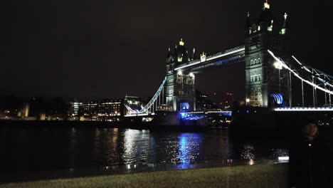 London-Tower-Bridge-at-night,-lit-up,-walking-towards-it,-looking-over-the-Thames