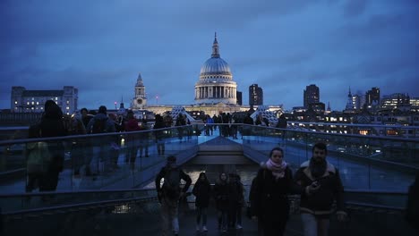 People-Walking-At-The-Millenium-Bridge-In-London,-UK-At-Dusk-With-The-Famous-Saint-Paul's-Cathedral-In-The-Background---Wide-Shot