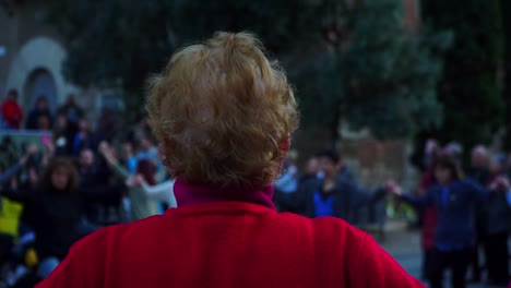 Close-up-Shot,-Elderly-Woman-in-Red-Sweater,-People-Dancing-and-Holding-hands-in-the-Background