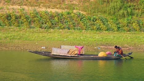 Two-fisherman-paddling-and-fishing-in-a-traditional-wooden-boat-in-Bangladesh