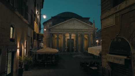 Aerial-view-over-streets,-towards-the-illuminated-Pantheon-temple,-night-in-Rome,-Italy---Low,-drone-shot