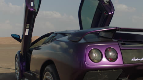Close-up-shot-of-purple-colored-Lamborghini-Diablo-parking-in-sandy-desert-of-Dubai