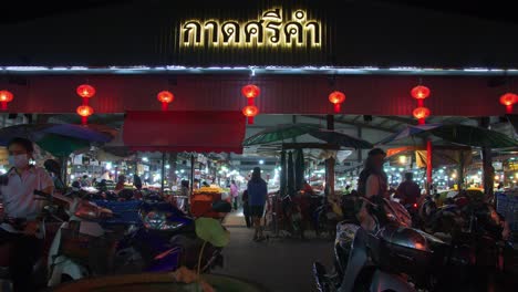 Aufnahme-Von-Einheimischen,-Die-Nachts-Einen-Belebten-Lokalen-Markt-Auf-Der-Anderen-Straßenseite-In-Der-Provinz-Nan,-Thailand-Betreten