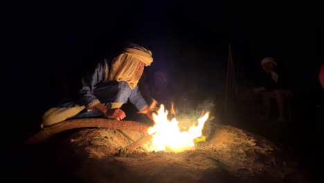 Traditional-indigenous-berber-boy-sits-at-campfire-at-night-in-Morocco