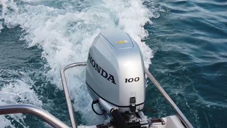 Close-up-on-a-Honda-outboard-engine-of-a-small-motorboat-cruising-the-sea---slow-motion
