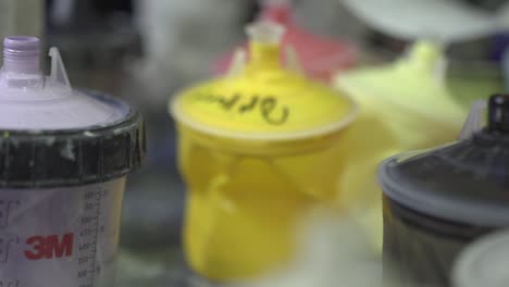 Close-up-of-multiple-cups-of-paints-with-liners-sitting-on-the-table-in-the-workshop