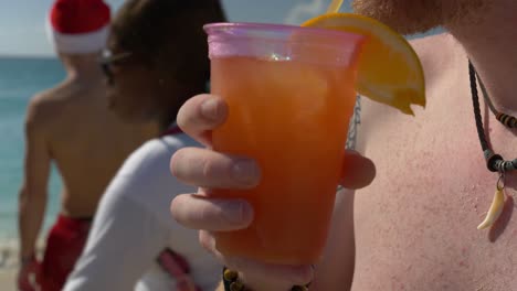 person-drinking-a-fresh-rum-punch-on-the-caribbean-Mahoa-airplane-beach-on-christmas-eve