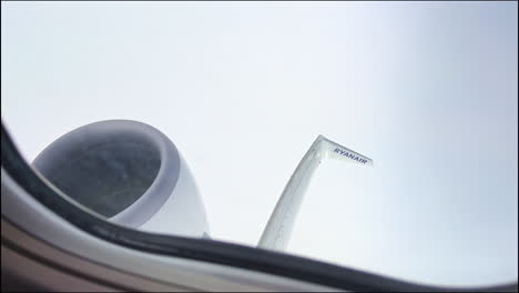 Ryanair-airplane-window-view-of-wing-and-engine-in-cloudy-turbulence