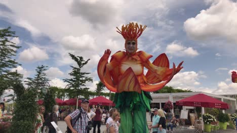 Gigantic-flowerman-mascot-performing-at-state-garden-show-Heilbronn-with-spectators-watching