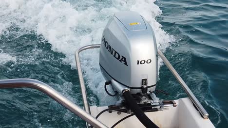 Pan-shot-on-a-Honda-outboard-engine-of-a-small-motorboat-cruising-the-sea---slow-motion