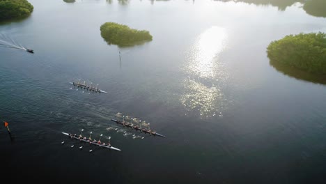 Aerial-Orbit-Shot-of-Rowing-Crew-at-Sunset-Finishing-at-Bridge