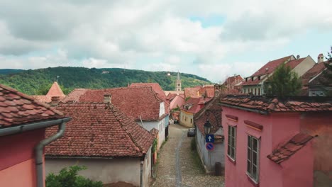 Backwards-drone-aerial-flight-through-tight-alley-in-ancient-city-of-Sighisoara-in-Romania