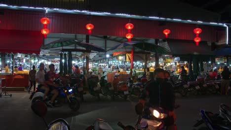 Shot-of-locals-walking-into-a-local-market-across-the-road-at-night-time-in-Nan-city,-Thailand