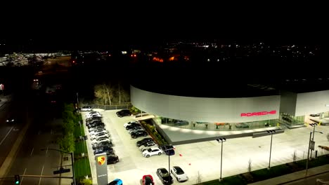 Aerial-view-of-Porsche-dealership-at-night-with-cars-for-sale-on-lot