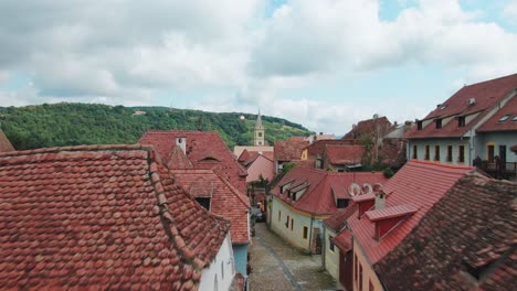 Drone-aerial-flight-through-tight-alley-rising-up-towards-old-church-in-Sighisoara-,-Romania