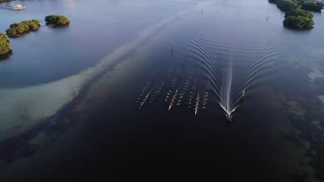 Aerial-Orbit-Shot-of-Crew-Rowing-off-into-the-Distance-at-Sunset