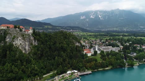 Drone-above-water-parallel-flying-view-Bled-lake-castle-on-cliff-summer