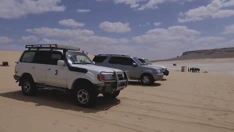 Camp-cars-parked-on-the-sand-under-a-cloudy-sky-in-the-desert---pan-right