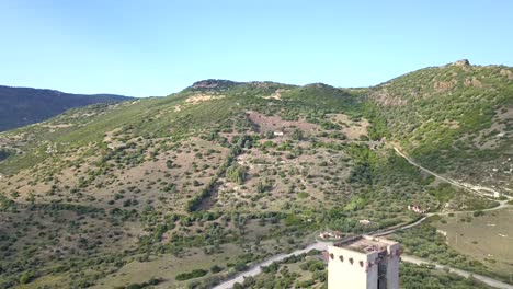 Drohnen-Luftaufnahme,-Die-Rückwärts-Fliegt-Und-Eine-Burg-Entdeckt,-Die-Die-Farbenfrohe-Stadt-Bosa-Auf-Sardinien-Dominiert,-Eine-Perfekte-Italienische-Und-Mediterrane-Landschaft