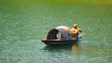 Static-medium-shot-of-bengali-man-fishing-from-canoe-on-river