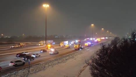 Cars-driving-slow-behind-plowing-trucks-cleaning-a-highway,-during-a-snow-storm,-at-night
