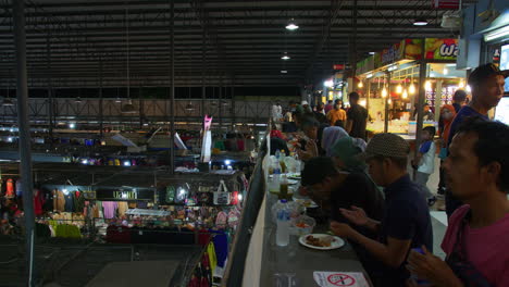 Turistas-Disfrutando-De-Comida-Callejera-Tailandesa-En-El-Bazar-Nocturno-De-La-ASEAN,-Hat-Yai,-Tailandia