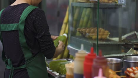 street-food-market-stand,-asiatic-woman-frying-tasty-crispy-food
