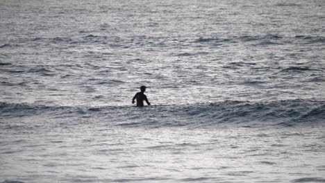 Einsamer-Surfer-Im-Meer,-Der-In-Der-Abendsonne-Auf-Einem-Surfbrett-Sitzt