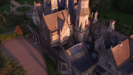 Luftaufnahme-Des-Herrenhauses-Am-See-Cheltenham,-Gloucestershire,-Haus,-Das-Vom-See-Aus-In-Wunderschönem-Goldenen-Abendlicht-Sichtbar-Wird