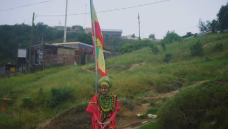 Mujer-Rastafari-Caucásica-Está-Detrás-De-La-Bandera-Rastafari-Plaza-Judá