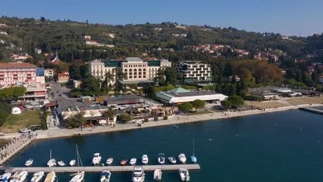 Drone-Adelante-Volando-Sobre-La-Zona-De-Atraque-De-Barcos-En-Trieste-Hacia-El-Hotel-Kempinski-Palace